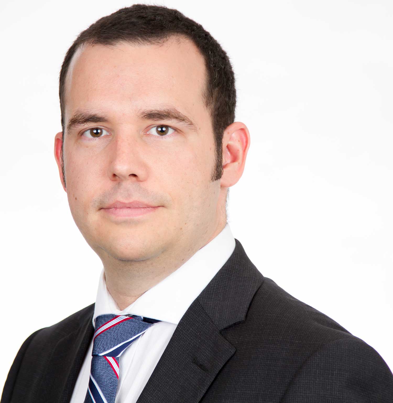 man with short brown hair wearing dark suit and striped tie