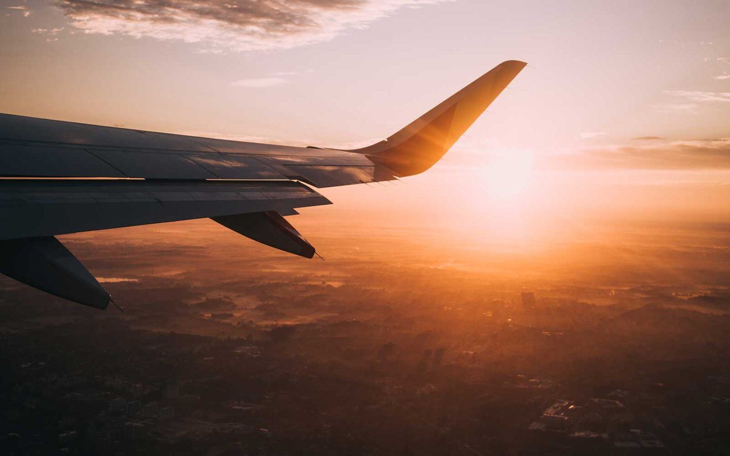 flying plane wing with sun in the background