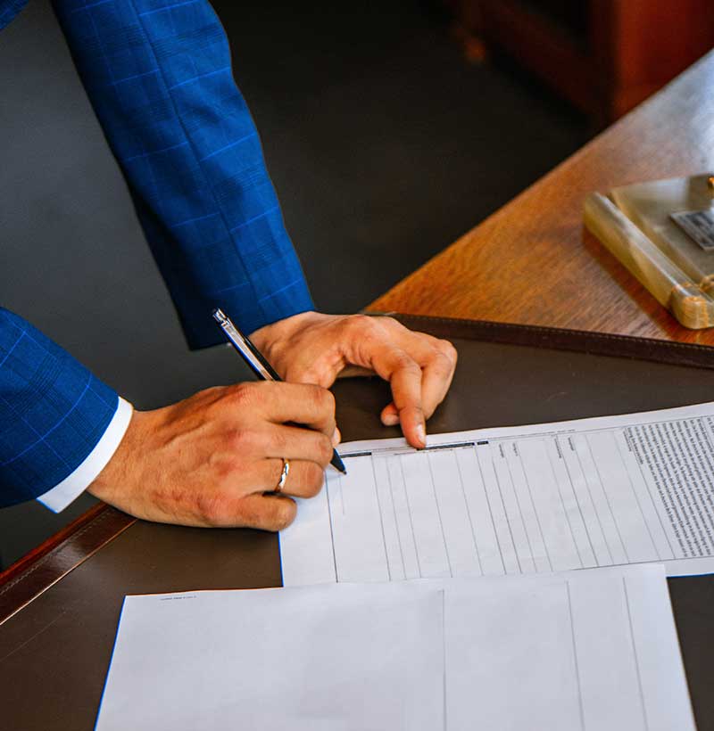 arm of man in blue suit holding pen writing on paper