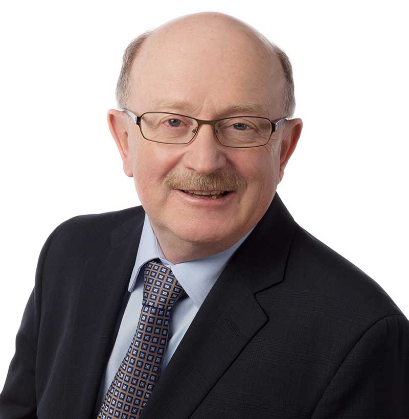 smiling man with moustache and glasses wearing black suit