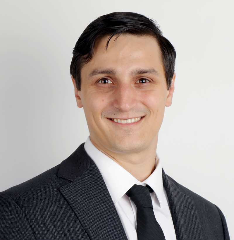 smiling clean-shaven man in dark suit and tie